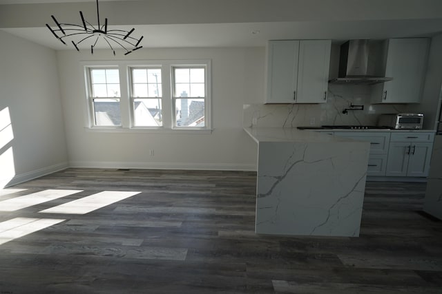 kitchen featuring pendant lighting, white cabinetry, wall chimney exhaust hood, and tasteful backsplash