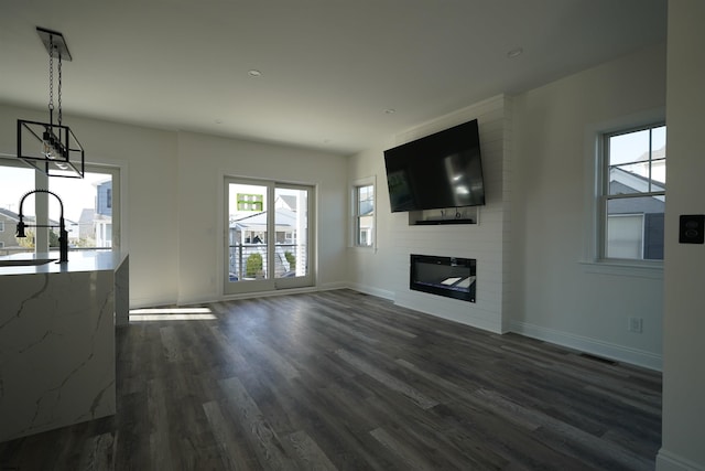 unfurnished living room featuring a large fireplace and dark hardwood / wood-style floors