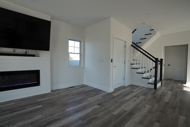 unfurnished living room featuring a large fireplace and dark hardwood / wood-style flooring