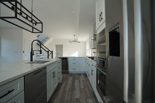 kitchen featuring stainless steel appliances, dark hardwood / wood-style flooring, hanging light fixtures, white cabinets, and sink