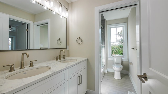 full bathroom featuring shower / bath combination with glass door, wood-type flooring, vanity, and toilet