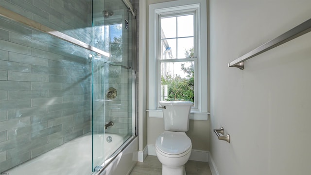 bathroom featuring toilet and bath / shower combo with glass door