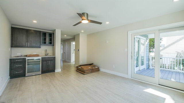 kitchen featuring wine cooler, dark brown cabinetry, light hardwood / wood-style flooring, and sink