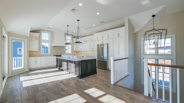 kitchen featuring high quality fridge, white cabinetry, a center island, and custom exhaust hood