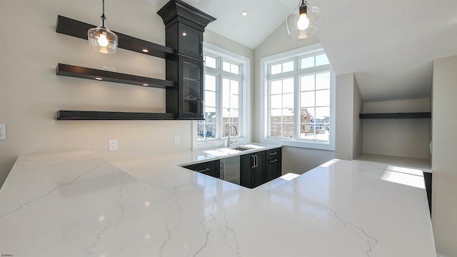 kitchen with lofted ceiling, sink, light stone countertops, and hanging light fixtures