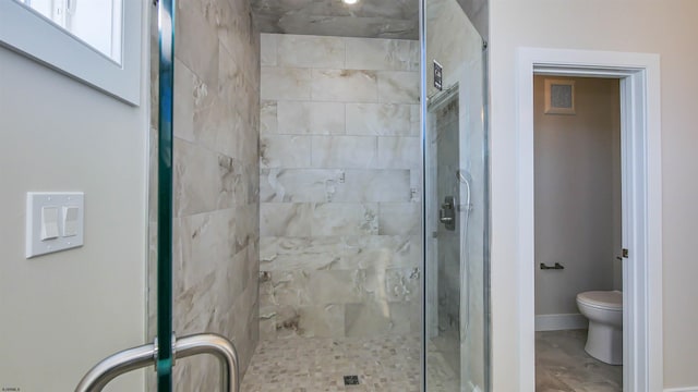 bathroom featuring toilet and a shower with shower door