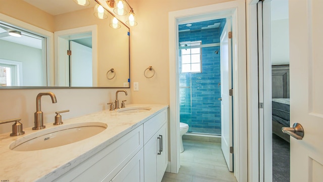 bathroom with a tile shower, vanity, toilet, and plenty of natural light