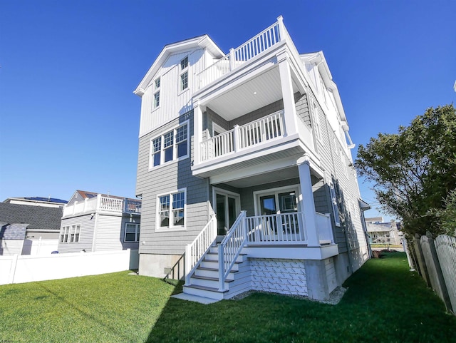 view of front of property featuring covered porch, a balcony, and a front yard