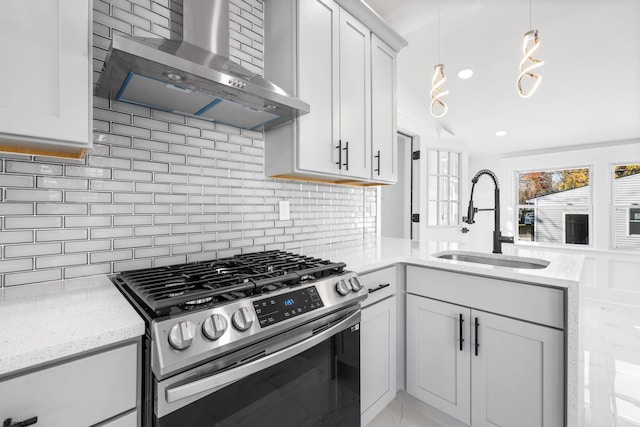 kitchen with backsplash, wall chimney range hood, sink, hanging light fixtures, and stainless steel gas stove