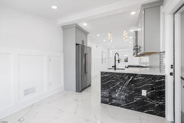 kitchen with high end refrigerator, light stone counters, sink, pendant lighting, and gray cabinets