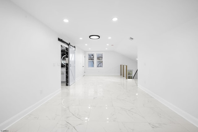 corridor with a barn door and lofted ceiling