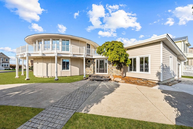 view of front facade featuring a balcony and a front lawn