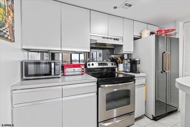 kitchen featuring white cabinets, light tile patterned flooring, and stainless steel appliances