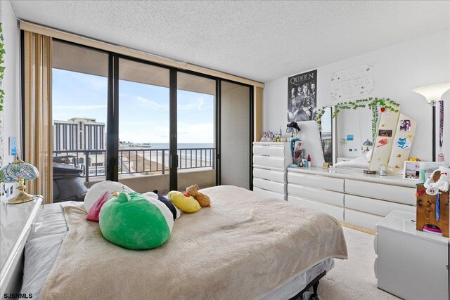 bedroom featuring a textured ceiling, expansive windows, multiple windows, and light colored carpet