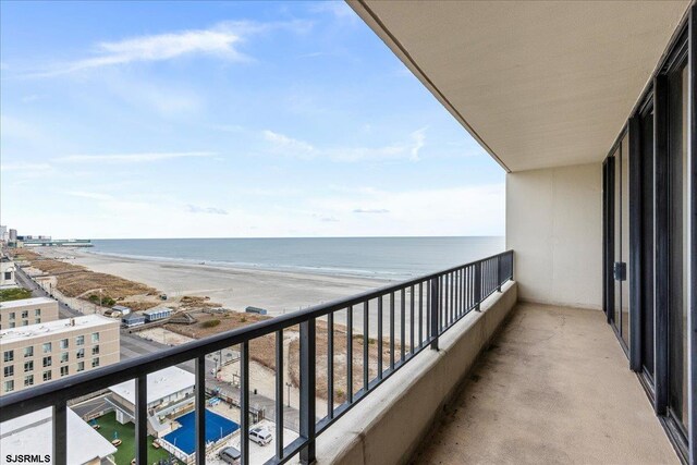 balcony with a water view and a view of the beach