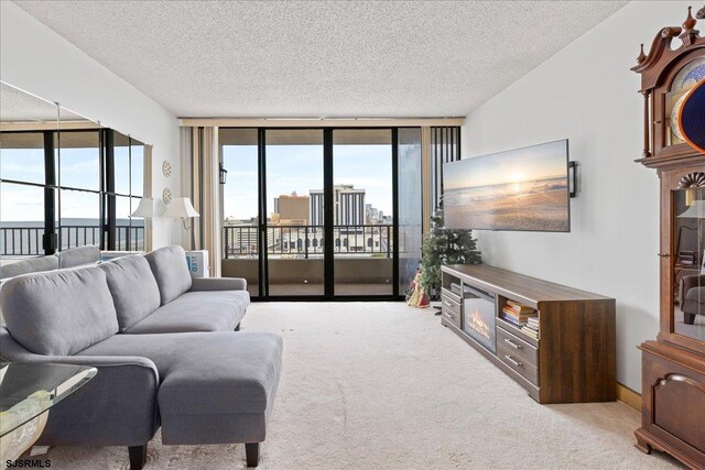 living room with a wealth of natural light, light colored carpet, a textured ceiling, and a wall of windows