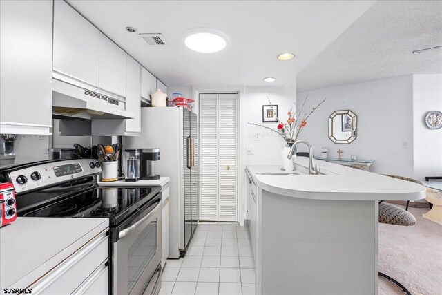 kitchen featuring white cabinetry, sink, light tile patterned floors, a breakfast bar, and stainless steel range with electric cooktop