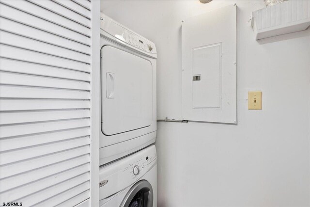 clothes washing area with electric panel and stacked washer / drying machine