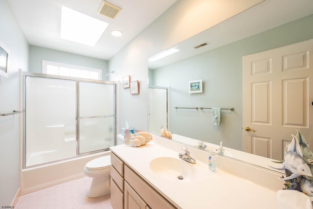 full bathroom with combined bath / shower with glass door, vanity, a skylight, and toilet