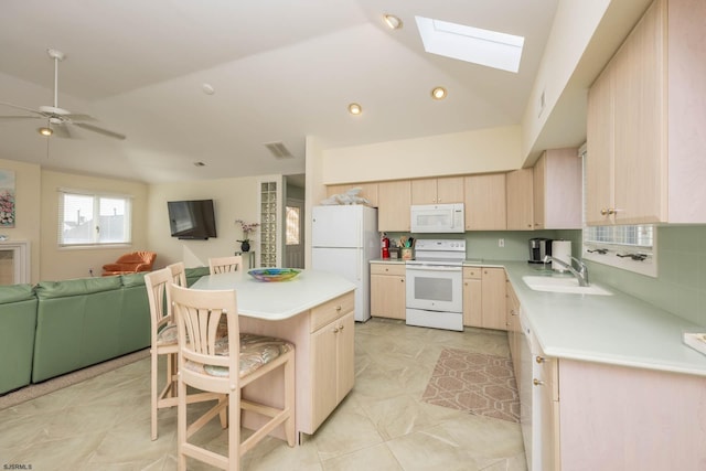 kitchen with ceiling fan, sink, lofted ceiling with skylight, white appliances, and a kitchen island