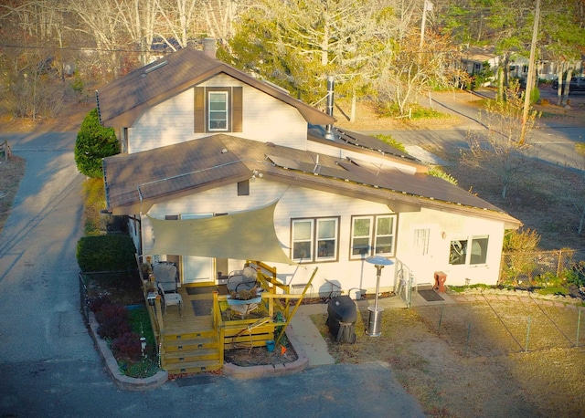 back of property with a deck and solar panels