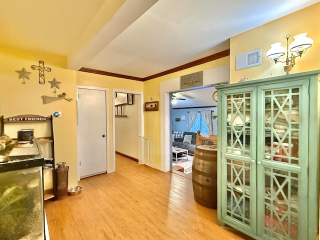 interior space with ceiling fan with notable chandelier, ornamental molding, and light hardwood / wood-style flooring