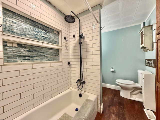 bathroom with hardwood / wood-style floors, tiled shower / bath, and toilet