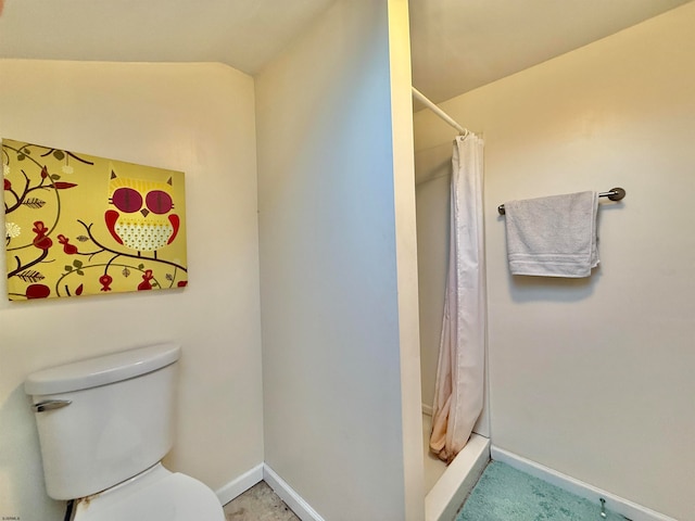 bathroom featuring a shower with shower curtain, vaulted ceiling, and toilet