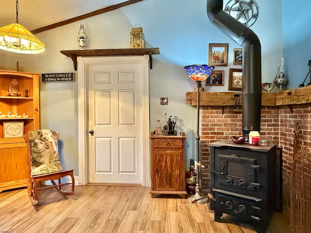 bar with lofted ceiling, light wood-type flooring, a wood stove, and hanging light fixtures