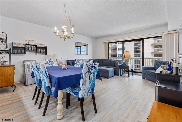 dining area featuring light hardwood / wood-style floors, a textured ceiling, and an inviting chandelier