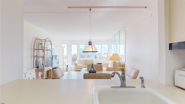 kitchen featuring sink, a textured ceiling, and hanging light fixtures