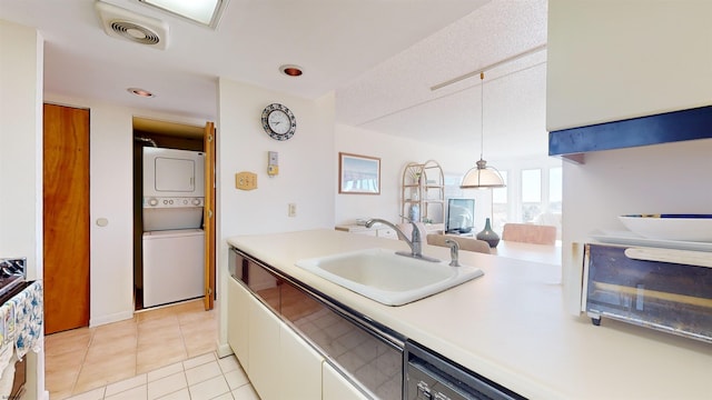 kitchen with pendant lighting, white cabinets, sink, light tile patterned floors, and stacked washer / drying machine