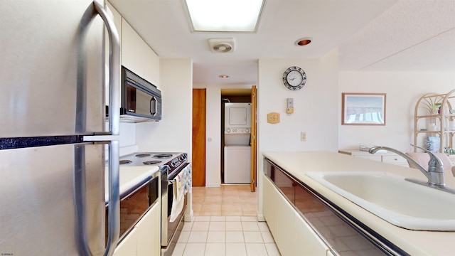 kitchen featuring white cabinets, sink, white electric stove, stainless steel fridge, and stacked washing maching and dryer