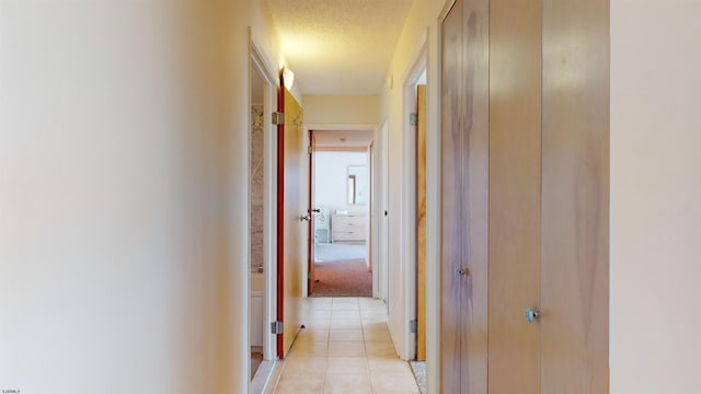 corridor featuring light tile patterned flooring and a textured ceiling