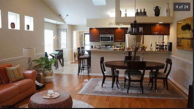 kitchen featuring stainless steel appliances, a kitchen breakfast bar, light stone counters, kitchen peninsula, and light wood-type flooring