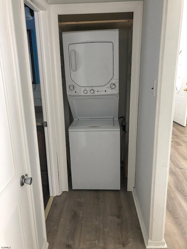 clothes washing area with hardwood / wood-style flooring and stacked washer / dryer