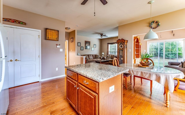 kitchen featuring pendant lighting, a kitchen island, light stone counters, and light wood-type flooring