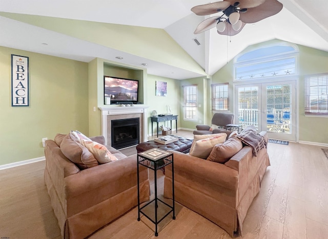 living room featuring a tile fireplace, french doors, vaulted ceiling, ceiling fan, and light wood-type flooring