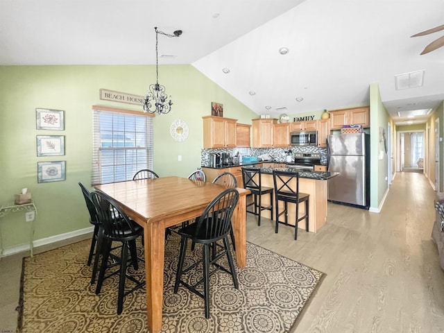 dining space featuring light hardwood / wood-style floors, vaulted ceiling, and ceiling fan