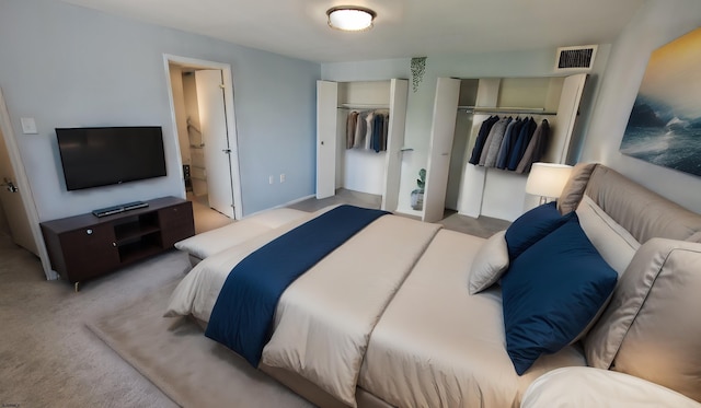 bedroom with light carpet and two closets