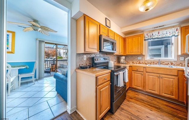 kitchen with sink, wood-type flooring, backsplash, and appliances with stainless steel finishes