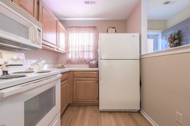 kitchen with light brown cabinetry, white appliances, and light hardwood / wood-style flooring