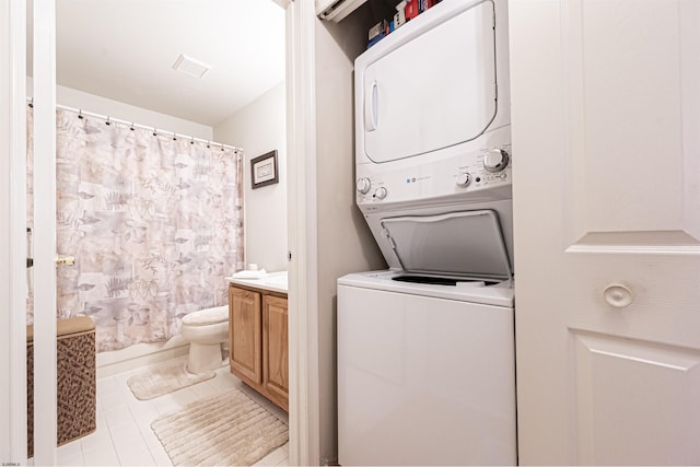 laundry room with light tile patterned floors and stacked washer and clothes dryer