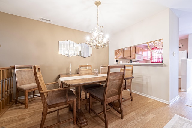 dining area with a chandelier and light hardwood / wood-style flooring