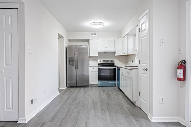 kitchen with appliances with stainless steel finishes, light hardwood / wood-style flooring, white cabinetry, and sink