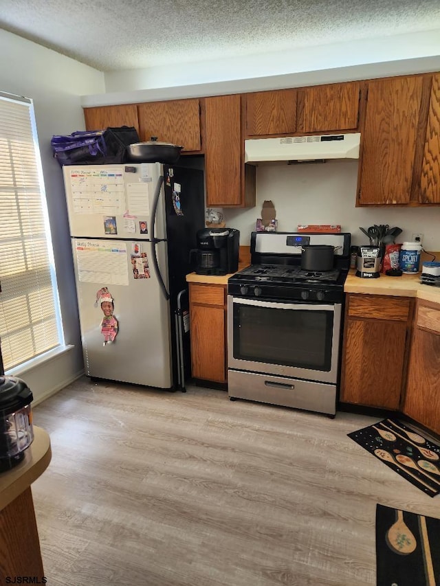 kitchen with light hardwood / wood-style floors, a textured ceiling, and appliances with stainless steel finishes