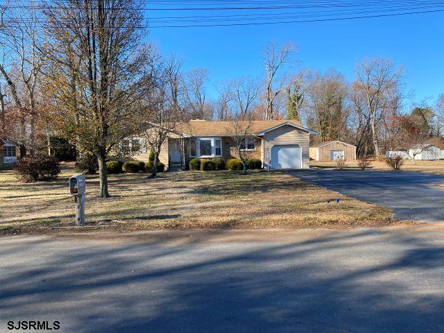 single story home featuring an outbuilding, a front lawn, and a garage