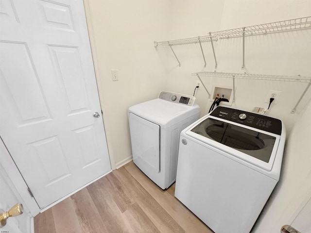 washroom featuring washing machine and dryer and light hardwood / wood-style flooring