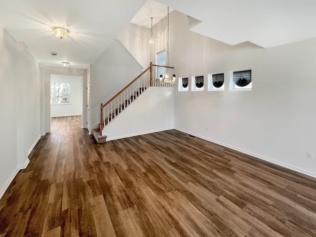 unfurnished living room featuring a notable chandelier and dark hardwood / wood-style floors