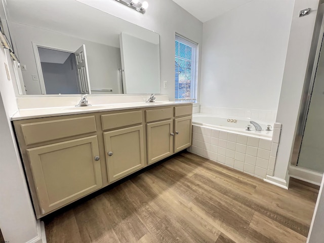 bathroom featuring vanity, hardwood / wood-style floors, and a relaxing tiled tub